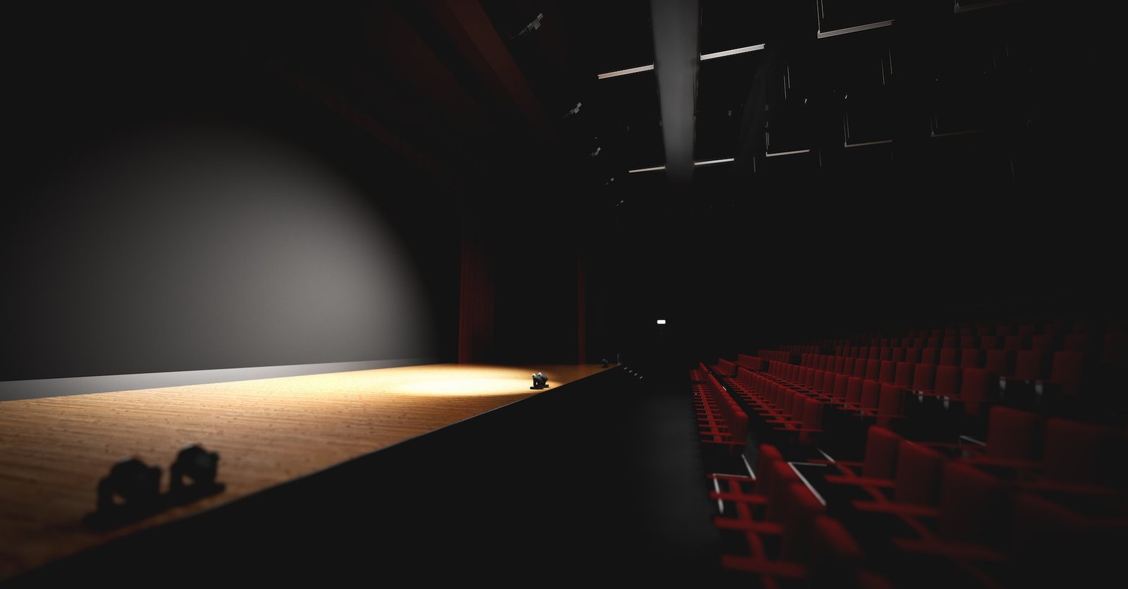 Theatre with empty stage in spotlight. Red theater curtain and seats